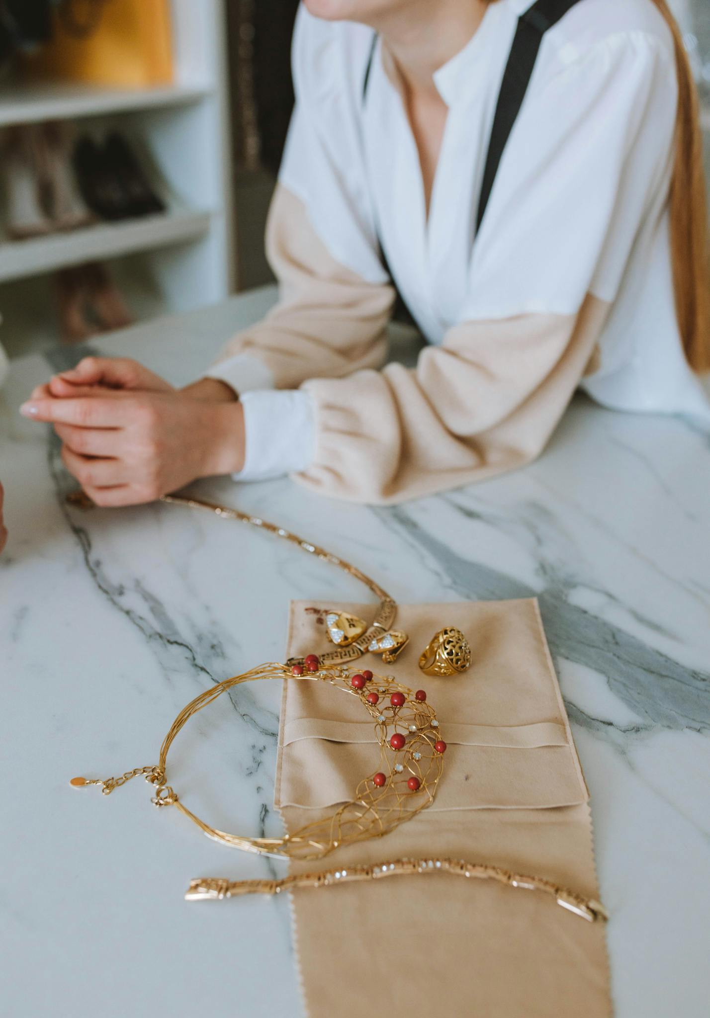 A woman enjoys elegant jewelry displayed on a marble counter indoors.