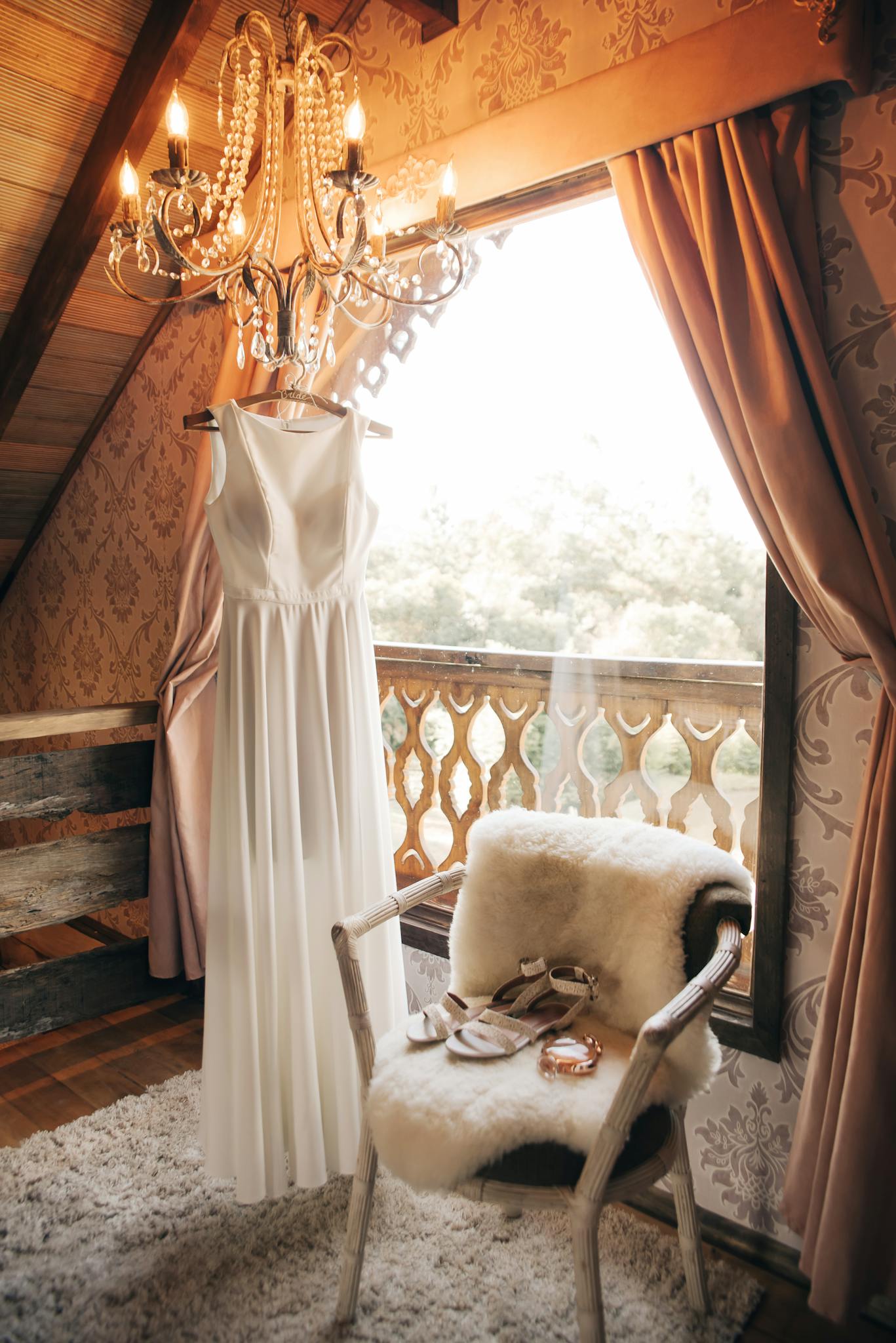 An elegant white wedding dress in a vintage-style room with chandelier lighting, evoking luxury and romance.